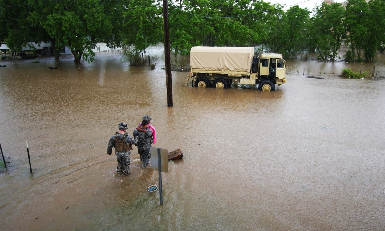 Rescue crews navigating contaminated floodwater through a residential area after severe flooding