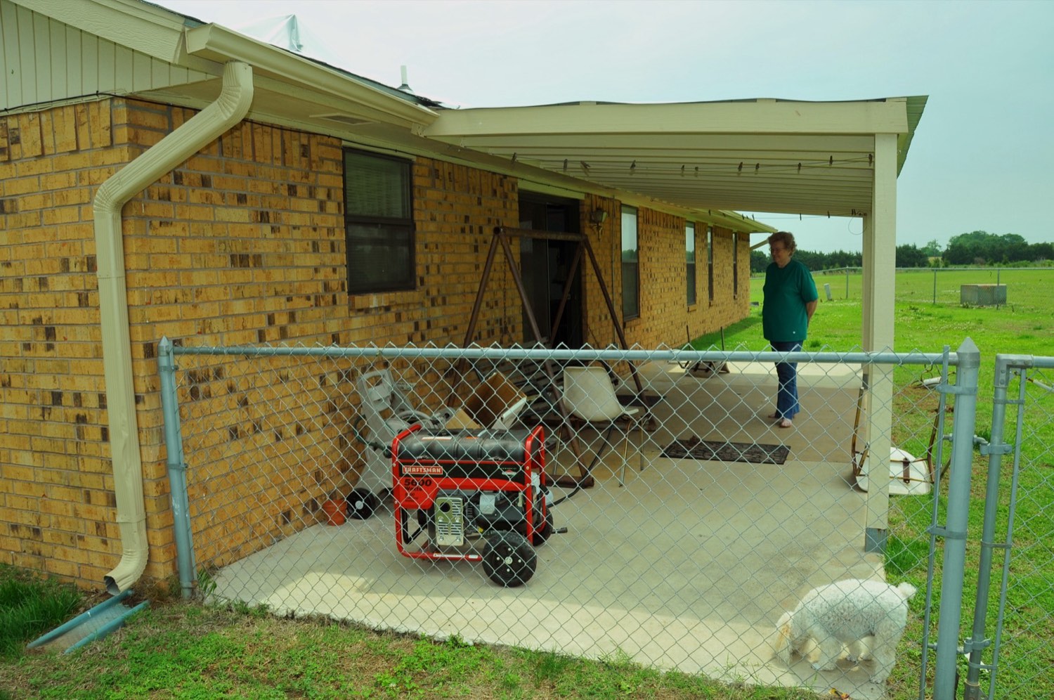 A portable gasoline generator running outdoors on a back patio, supplying power to a home during a power outage