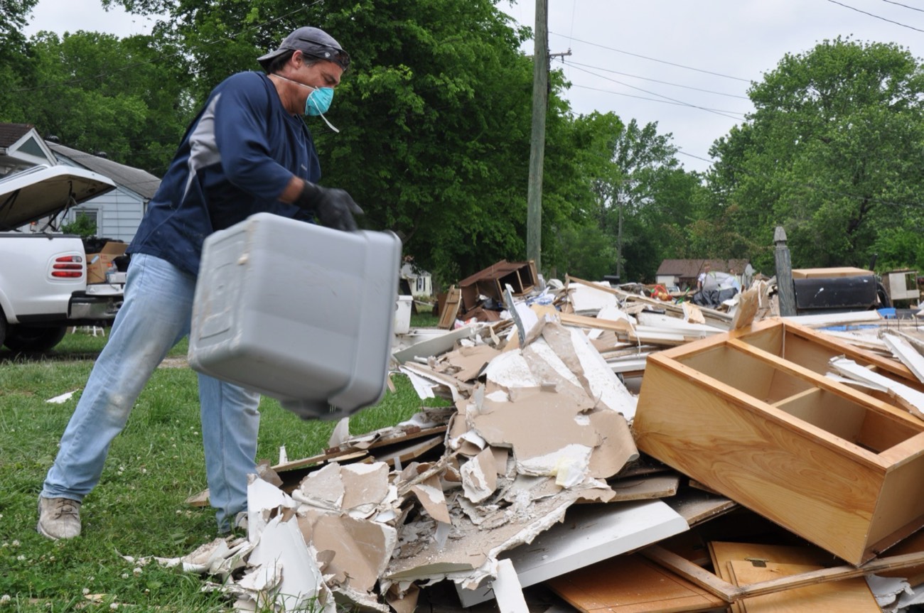 Residents and volunteers hauling water-damaged debris out of a flooded home during cleanup