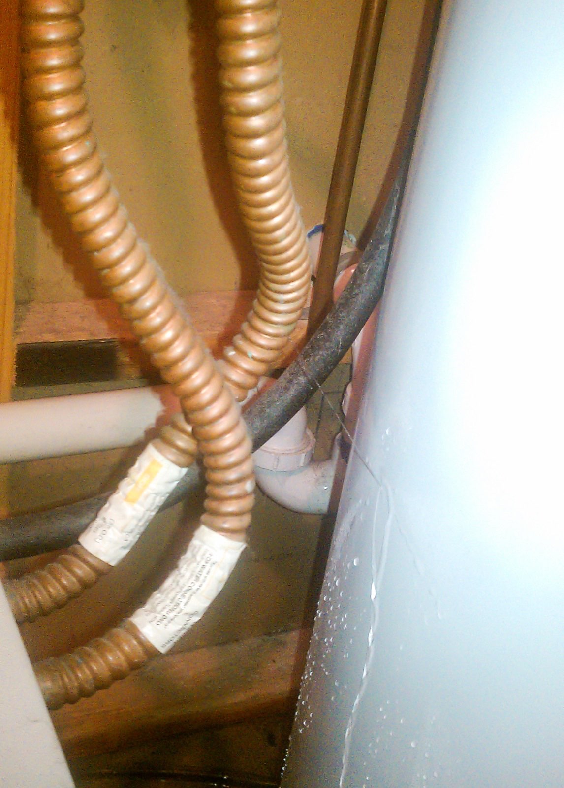 Water leaking from the base of a residential water heater tank onto the floor