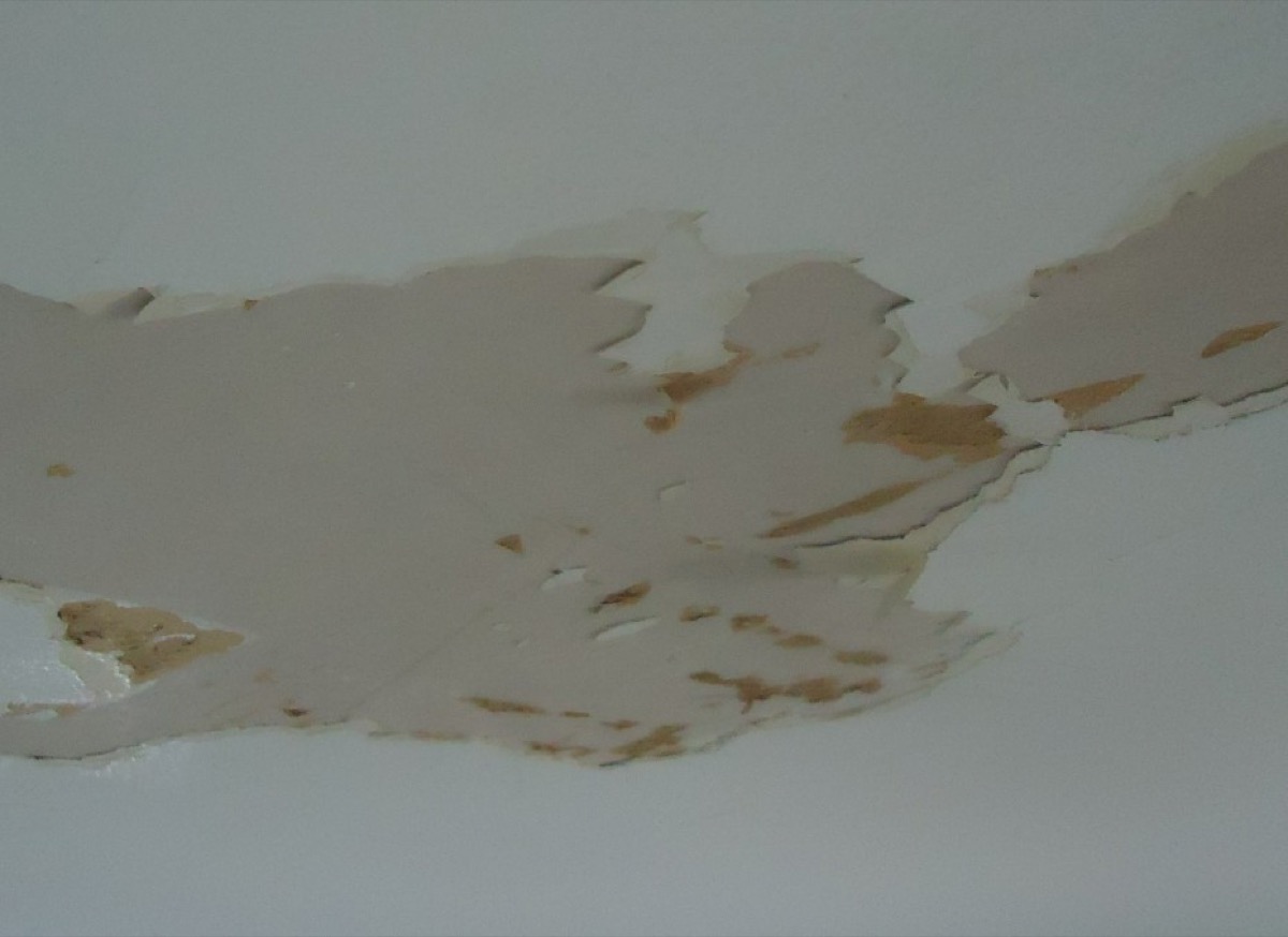 Water-damaged ceiling drywall with paint peeling and blistering from trapped moisture