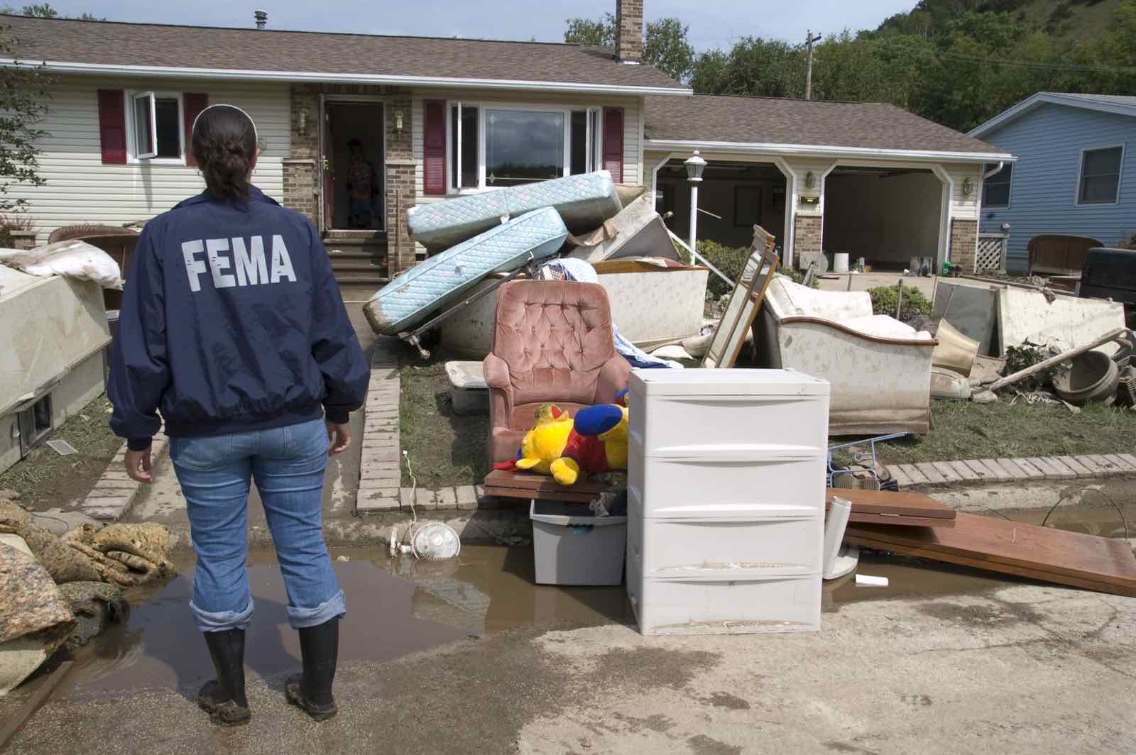 A FEMA representative examines a flood-damaged home in Minnesota, the kind of loss NFIP flood insurance is designed to cover