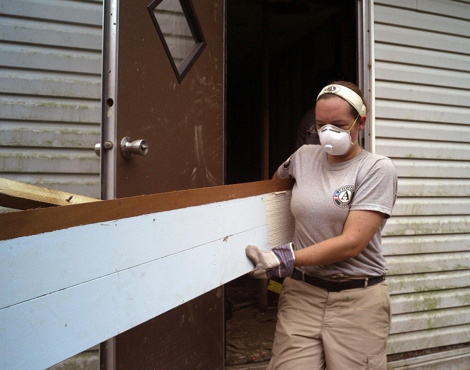 Volunteers carrying flood-damaged belongings out of a home to the curb during cleanup, deciding what to throw away after a flood